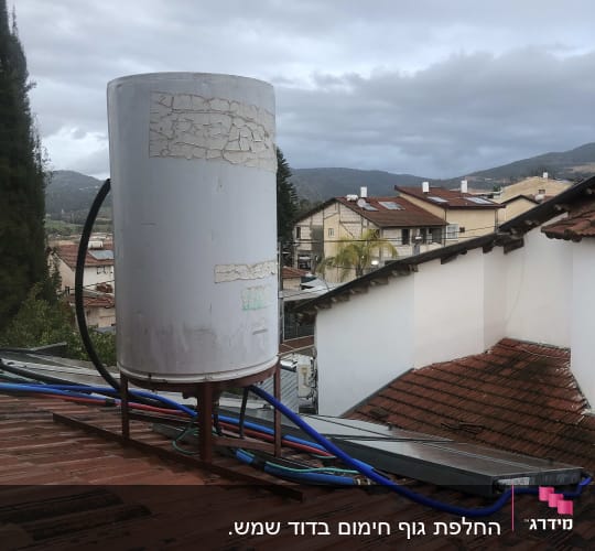 דוד שמש על גג עם צינורות כחולים ושחורים